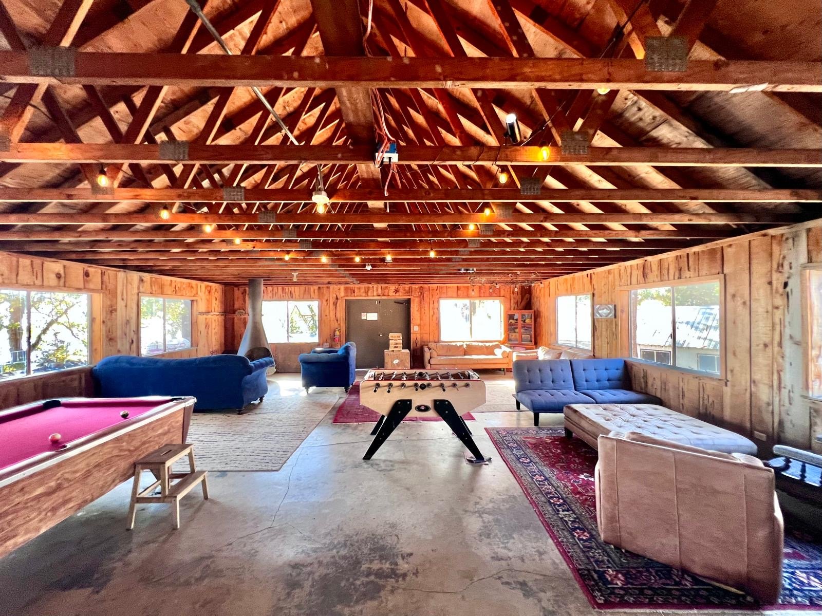 Inside the Bungalow: a wood-beamed hall with sofas, a pool table and foosball