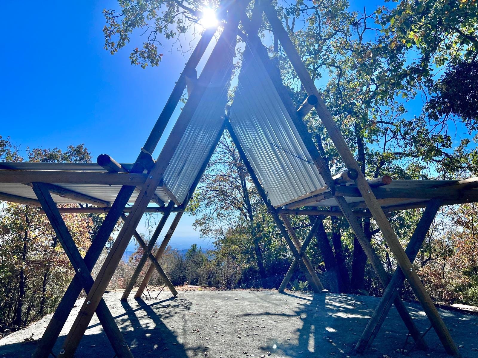 Open-air A-frame shade structures on the Plateau, with views over the valley