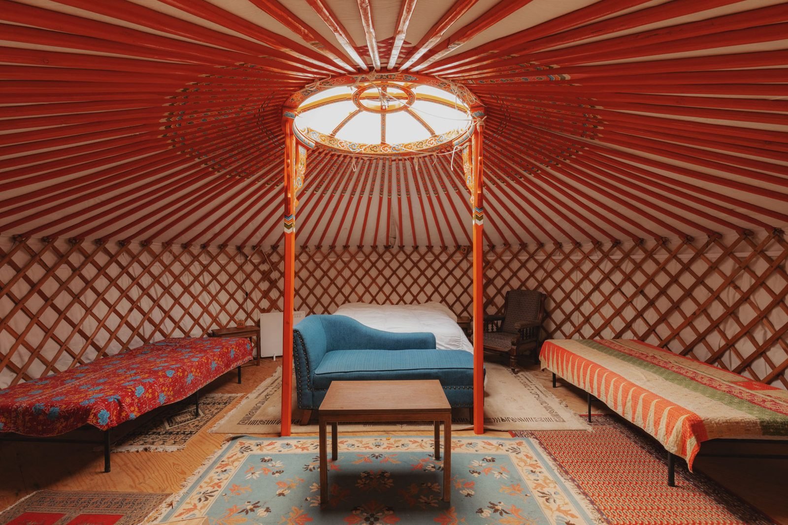 Inside a yurt with a red painted frame, skylight and beds